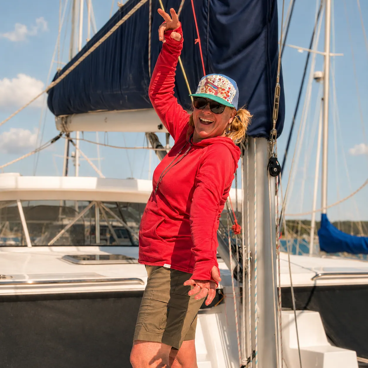 Woman in a red hoodie standing on the deck of an Antares catamaran.