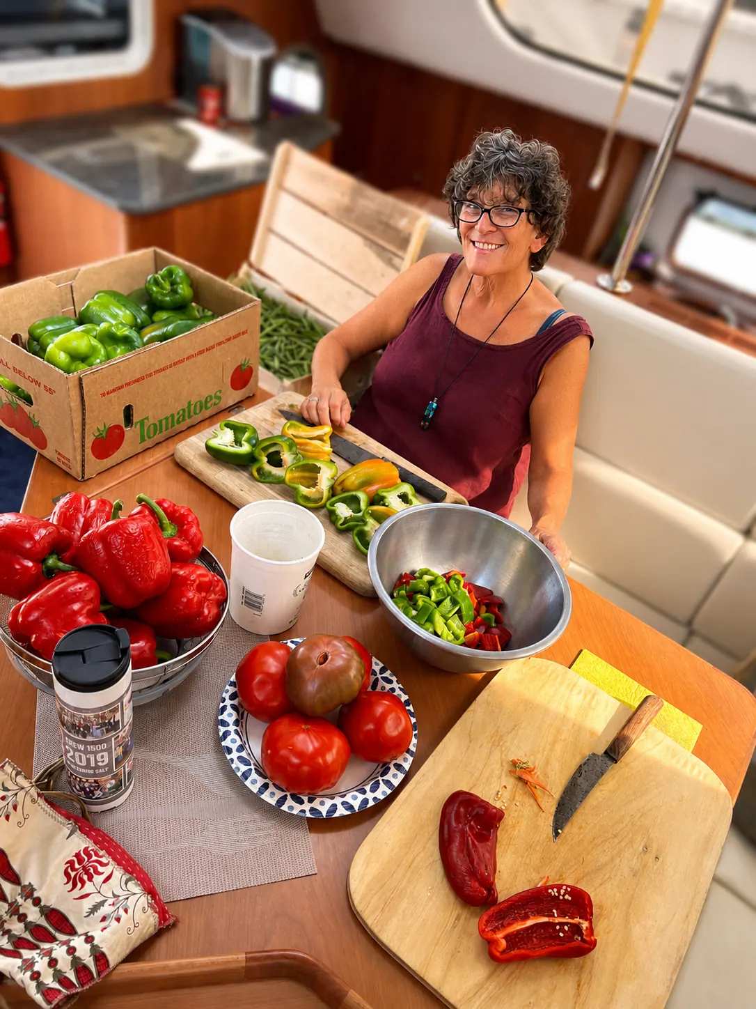 Fresh peppers and tomatoes being prepped in the galley aboard an Antares, illustrating a buy-fresh-late, eat-first provisioning routine for passage cooking.