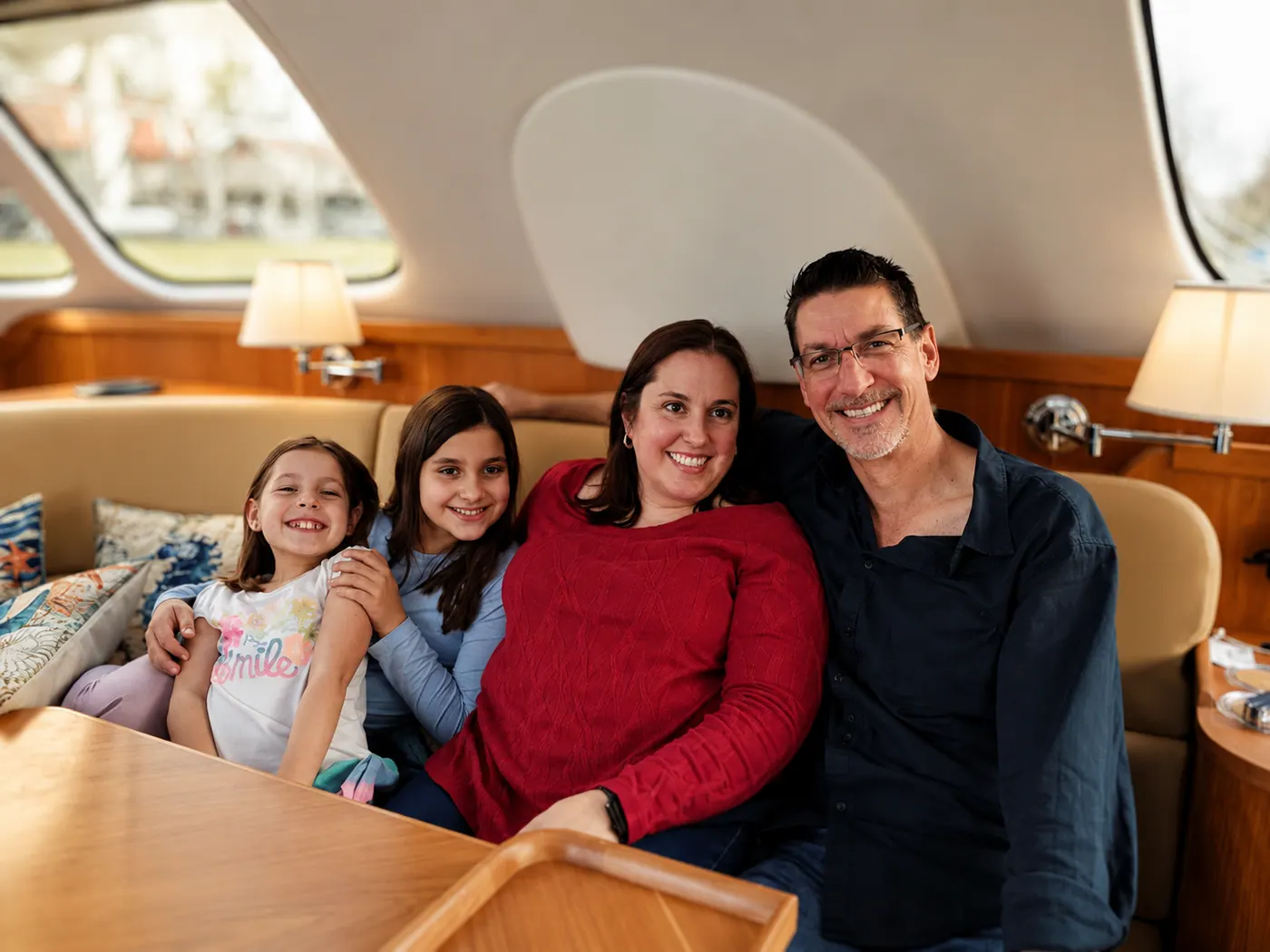 Jen, Ted, and their daughters seated together in the salon aboard Ohana, an Antares catamaran.