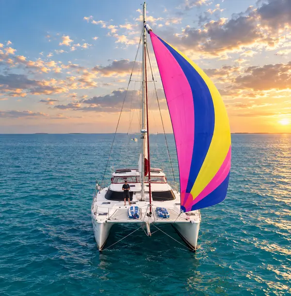 Bow view of Leap of Faith, a PDQ Antares 44, sailing under a colorful asymmetrical spinnaker at sunset