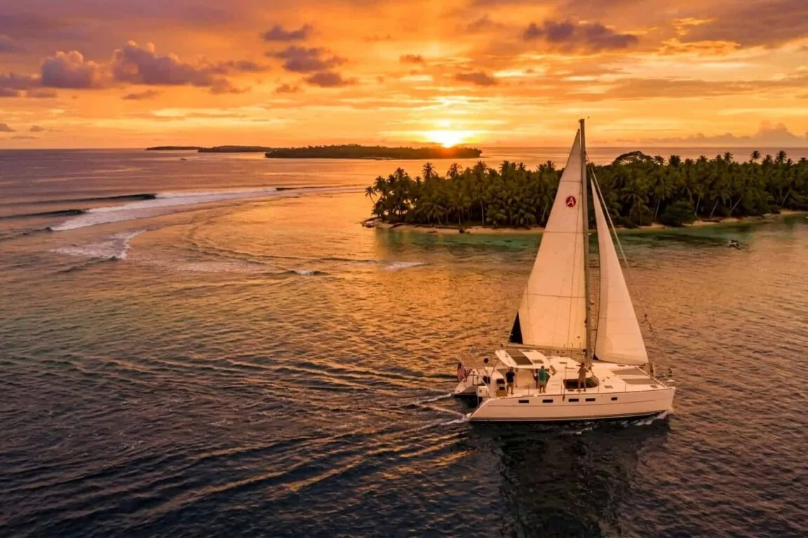 Antares owner catamaran anchored off a tropical island at sunset