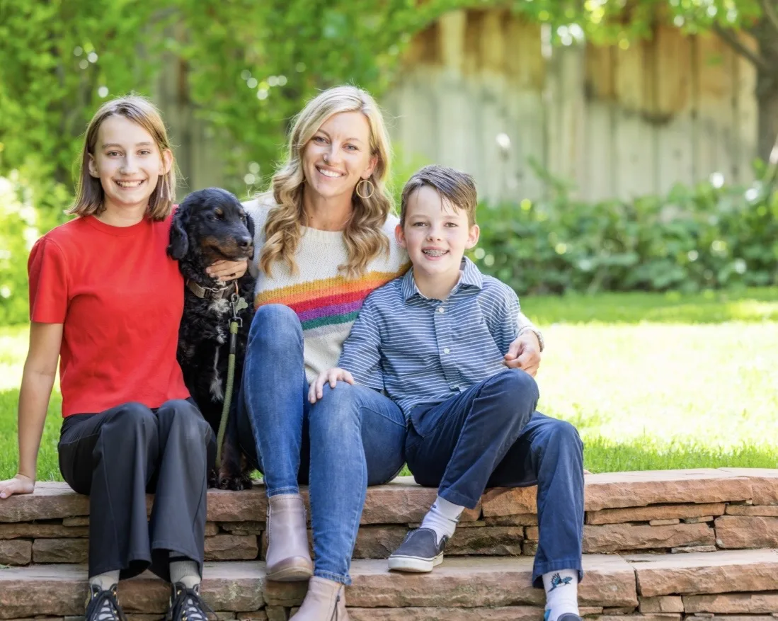 Heidi seated outdoors with her children, Piper and Cade, and their dog Charlie